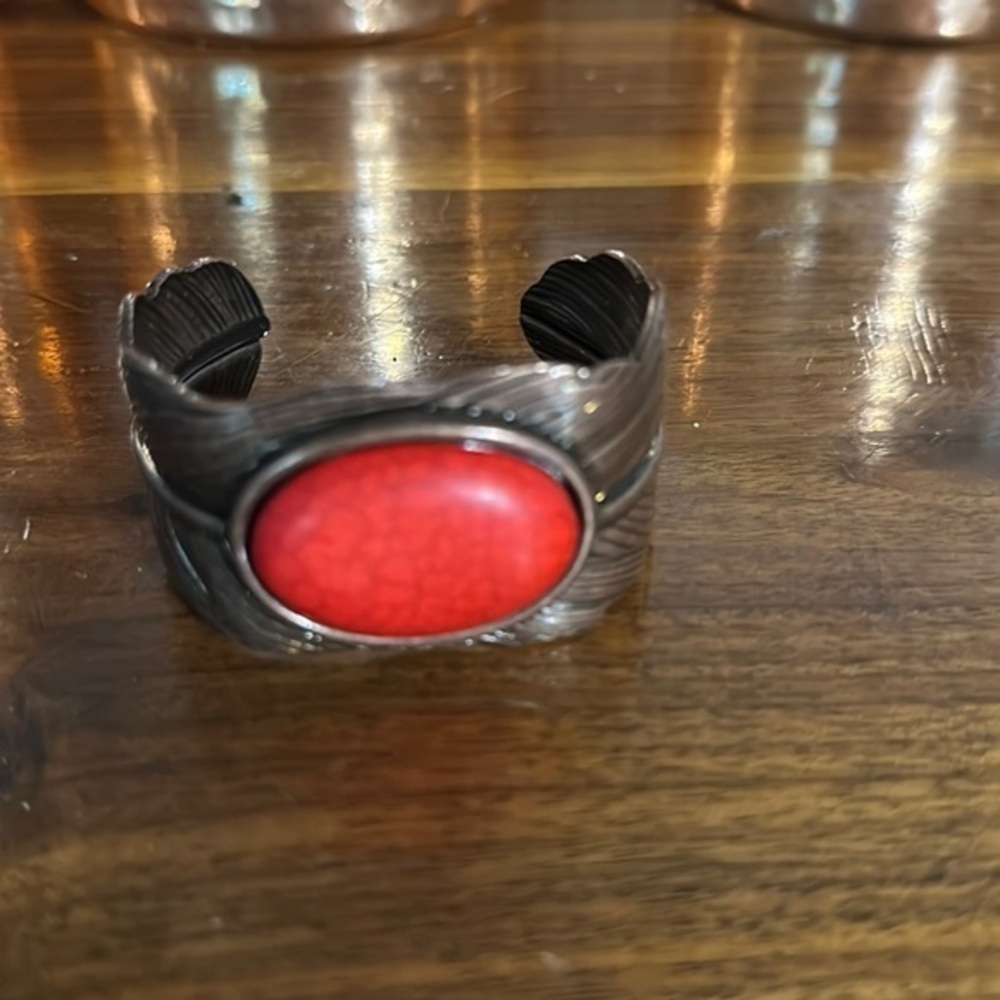 Copper tone cuff with coral colored stone.